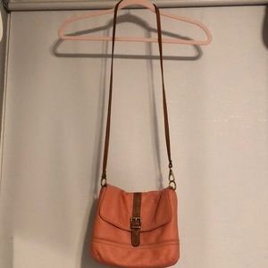 A peach colored cross body Fossil purse.